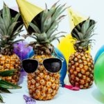 Three pineapples with balloons, party hats and sun glasses